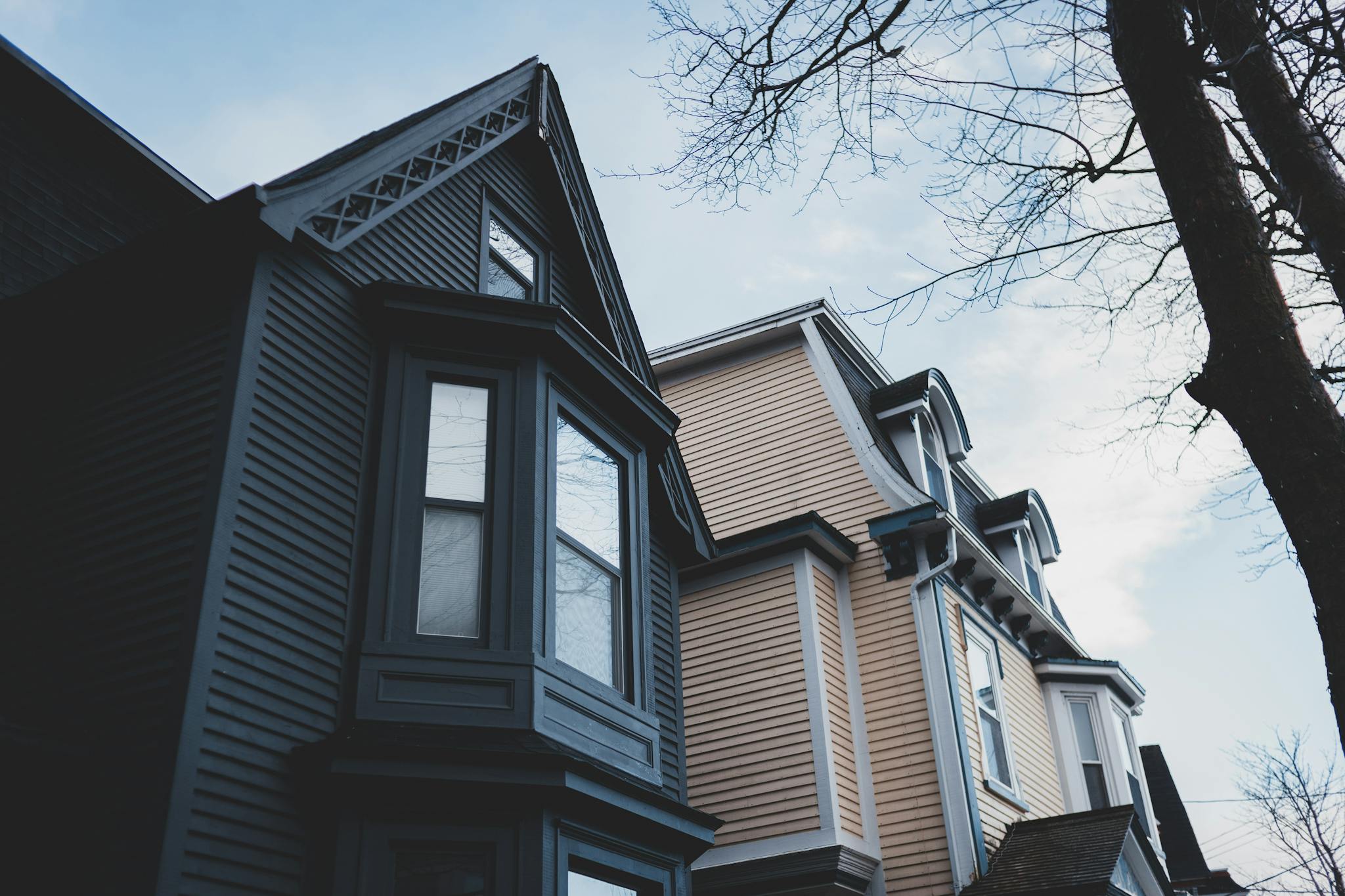 From below of exterior of modern residential building with windows and attic trimmed with dark gray wooden siding